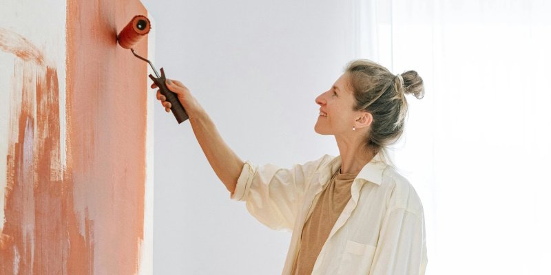 A woman painting a wall with a paint roller — DIY home improvement